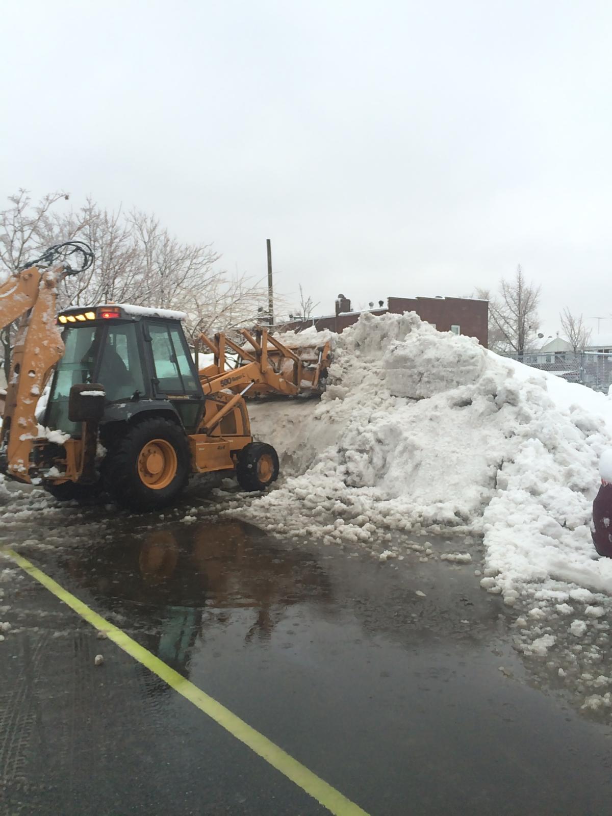 Snow plow loader clearing snow from a commercial parking lot