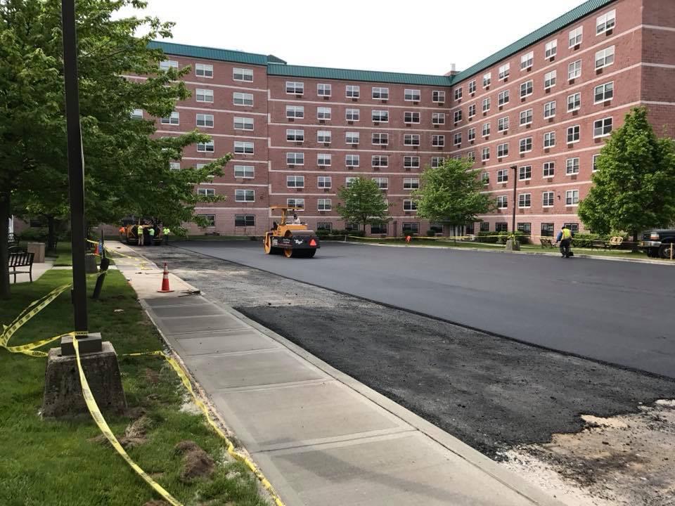 Commercial asphalt paving crew laying new blacktop on a parking lot