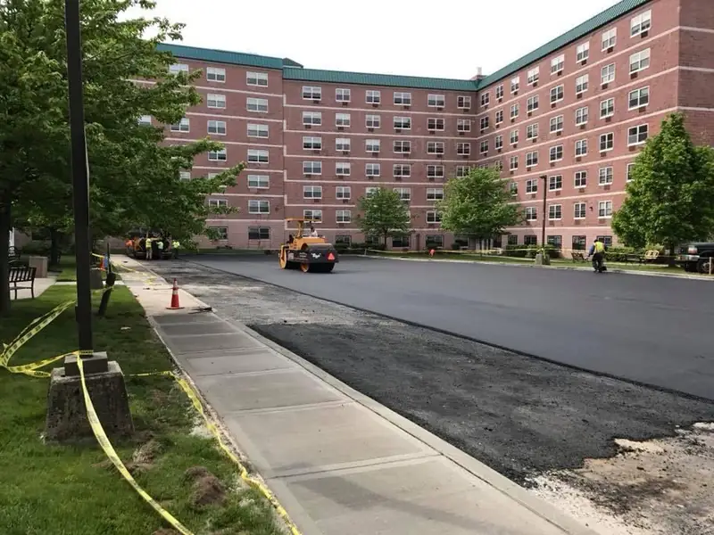 Commercial asphalt paving crew laying new blacktop on a parking lot