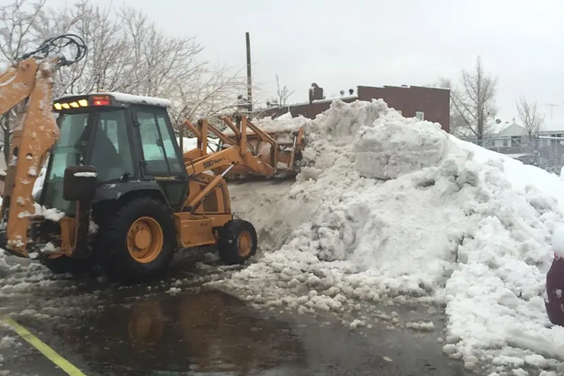 Snow plow loader clearing snow from a commercial parking lot